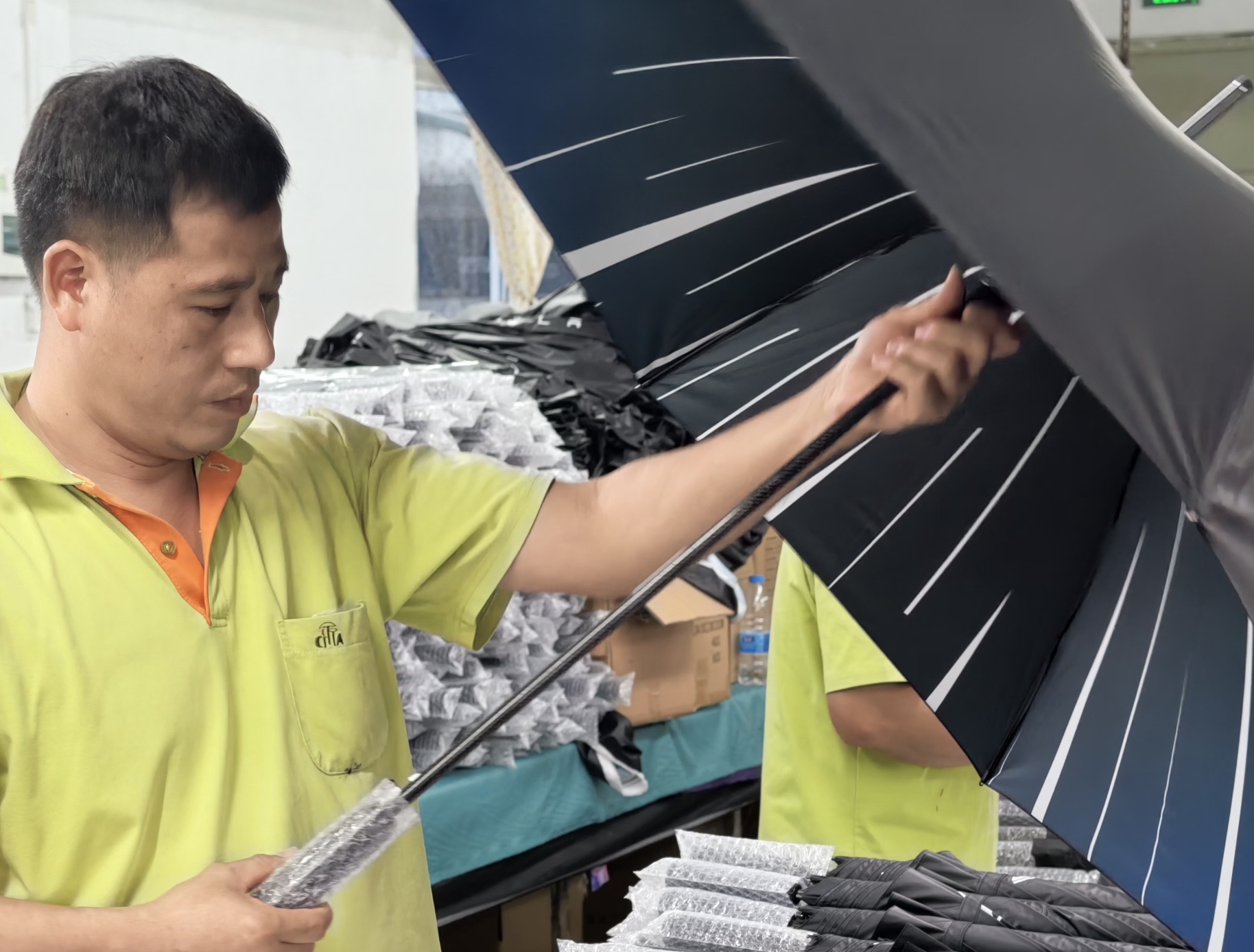 Un operario de CITTA inspecciona un paraguas de golf personalizado abierto durante el montaje