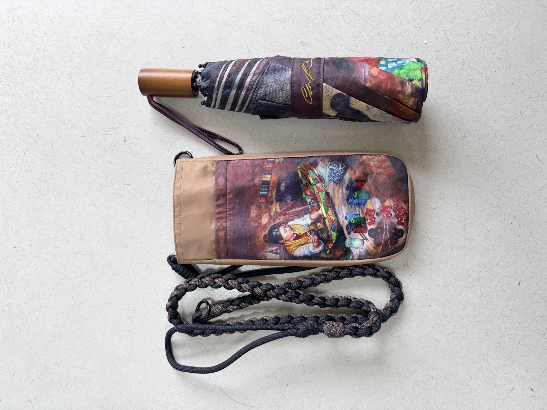 Paraguas artístico plegado con su funda y cordón de transporte