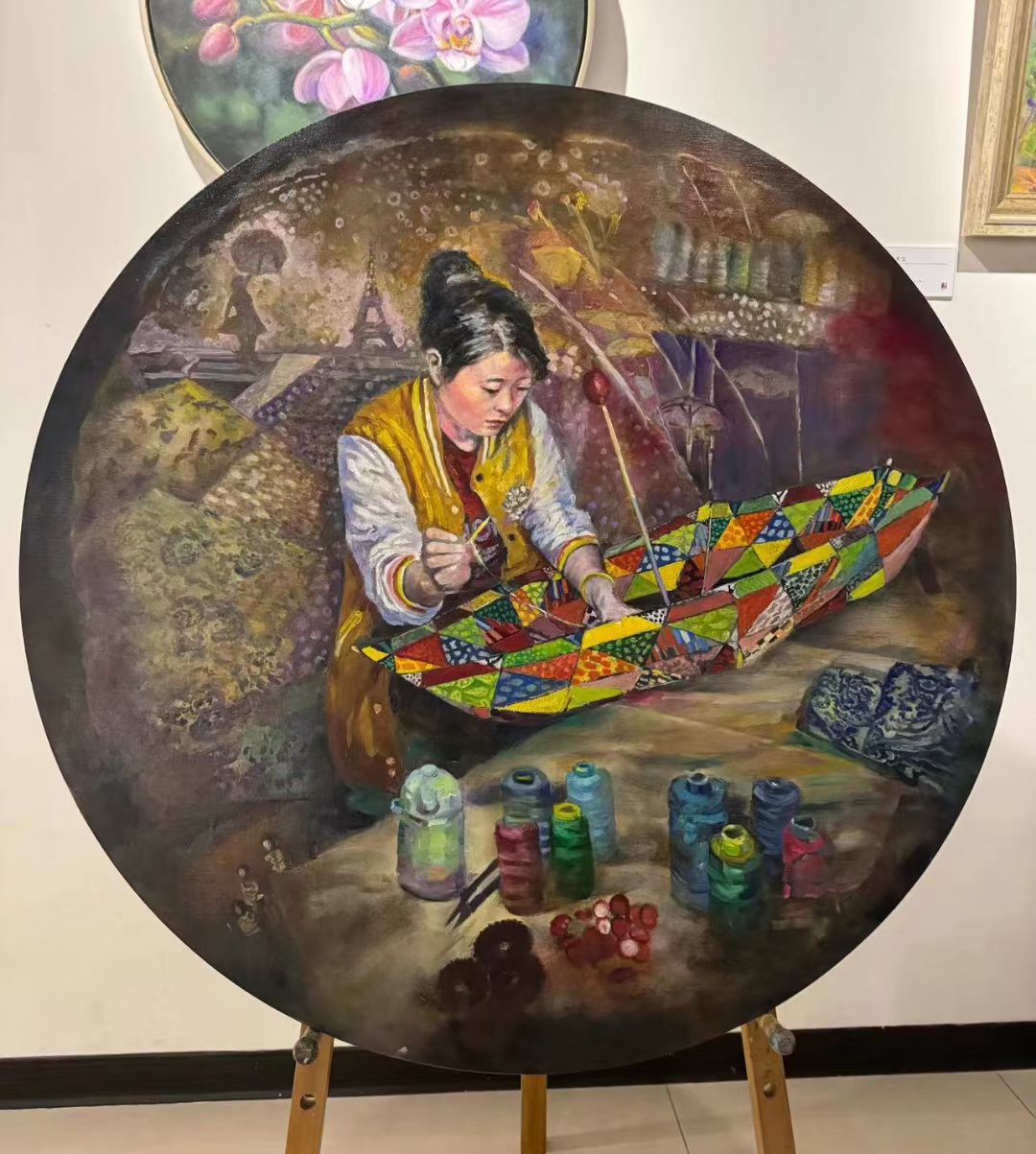 Pintura al óleo terminada que muestra a una trabajadora cosiendo paraguas, una cubierta y conos de hilo